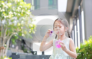 Happy little girl playing soap bubbles in garden