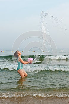 Happy little girl playing in water on the beach