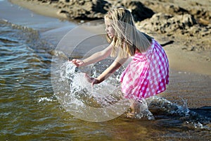 Happy little girl playing with water on the beach