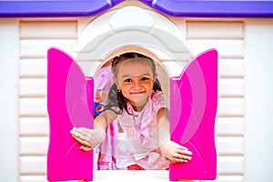 Happy little girl plays in the amusement park. Joyful child on vacation. Portrait of a girl on attractions