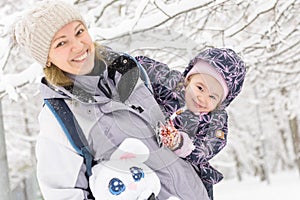 Happy little girl plays with mother in park in winter