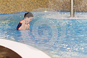 Happy little girl in the pool of the water park. Child learns to swim. teaching a child to swim