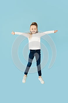 Happy Little Girl Posing In Mid Air Jumping, Blue Background