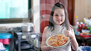 Happy little girl preparing homemade pizza in the home kitchen
