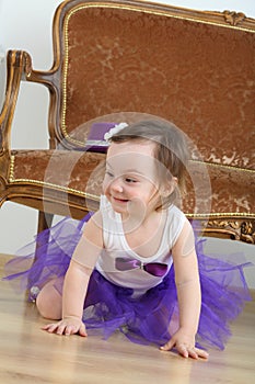 Happy little girl in purple skirt sitting on floor