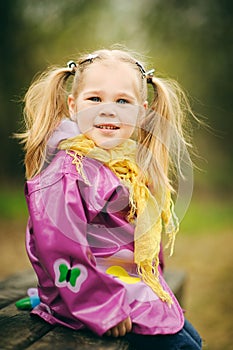 Happy little girl in raincoat at the park