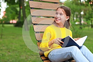 Happy little girl reading book in park