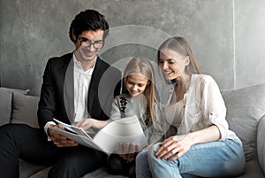 Happy little girl reads a book with her parents
