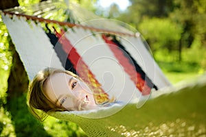 Happy little girl relaxing in hammock on beautiful summer day. Cute child having fun in spring garden