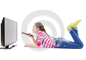Happy little girl with remote control watching tv photo