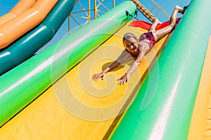 Happy little girl rides a water inflatable slide in a water Park, summer Sunny day, entertainment, water Park