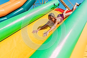 Happy little girl rides a water inflatable slide in a water Park, summer Sunny day, entertainment, water Park