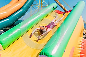 Happy little girl rides a water inflatable slide in a water Park, summer Sunny day, entertainment, water Park