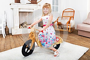 Happy little girl riding a runbike at home