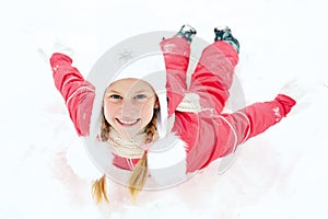 Happy little girl riding on snow slides in winter time