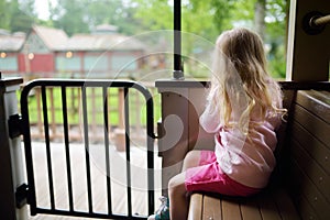 Happy little girl riding a train in a theme park or funfair
