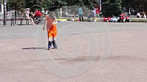 Happy little girl roller skates in summer town