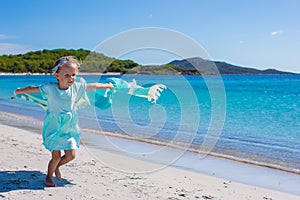 Happy little girl running along the beach with