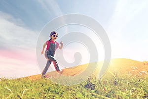 Happy little girl running on green summer field