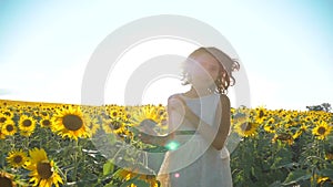 Happy little girl running happy free across the field with sunflowers. slow motion video. smelling big sunflower on