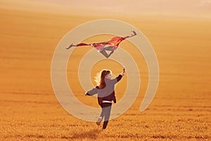 Happy little girl running with kite in hands on the beautiful field