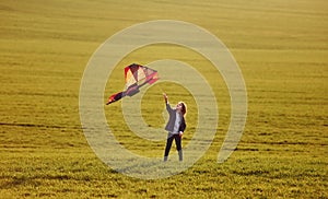 Happy little girl running with kite in hands on the beautiful field