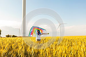 Happy Little girl running in a wheat field with a kite in the summer.