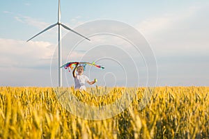 Happy Little girl running in a wheat field with a kite in the summer.