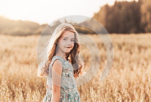 A happy little girl runs through a wheat field in the summer on a sunny day. Summertime. Summer vacation. Happy childhood.