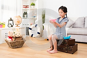 Happy little girl sailor sitting on retro suitcase