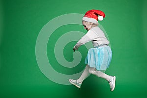 Happy little girl in Santa Claus hat jumping