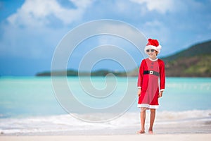 Adorable little girl in Santa hat on tropical beach