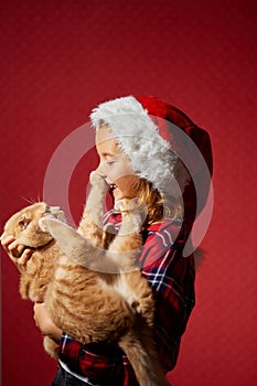 Happy little Girl in Santa Hat with joyfu funnyl cat in hand