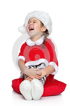 Happy little girl in Santa hat laughs on a white