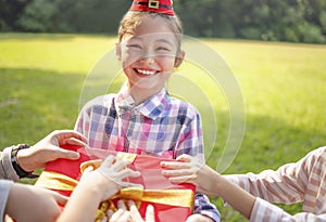 Happy little girl in Santa red hat and holding Christmas presents