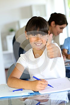 Happy little girl at school with thumb up