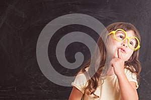 Happy little girl schoolgirl from the blackboard