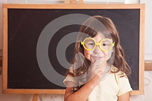 Happy little girl schoolgirl from the blackboard