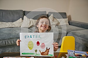 Happy little girl showing her beautiful drawing to the camera, Easter theme