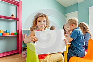 Happy little girl showing her drawing to the camera