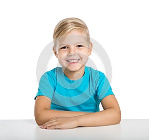 Happy little girl sits at a table and smile