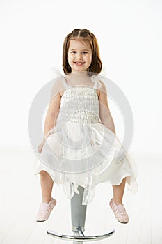 Happy little girl sitting on chair