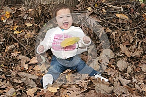 Happy little girl sitting in leaves