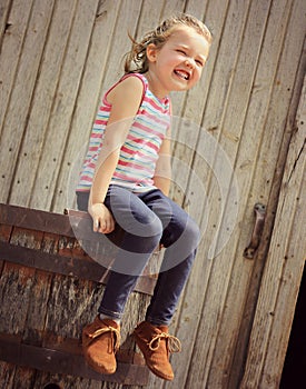 Happy little girl sitting on old barrel