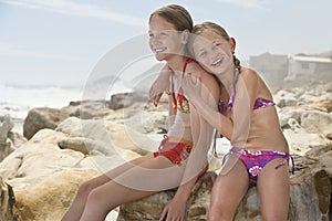 Happy Little Girl Sitting With Sister On Rocks