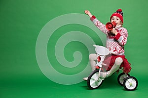 Happy little girl sitting on a small bike at Christmas time