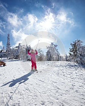 Happy little girl skiing downhill on sunny winter day