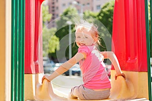 Happy little girl on slide at children playground