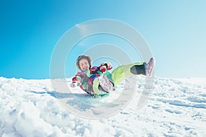 Happy little girl slides down from the snow slope. Enjoying the