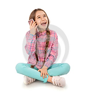 Happy little girl with smart phone sitting on floor isolated on white background. People, children, technology